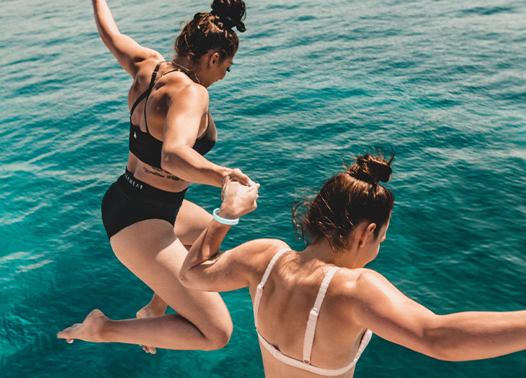 Two Topdeck travelers jumping into the clear waters of the Adriatic sea on a sailing trip in Croatia.