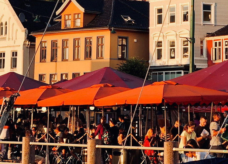 Restaurant patrons eating outside by the dockside in Bergen.
