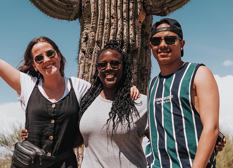 Travellers standing in front of a cactus in the Arizona desert.