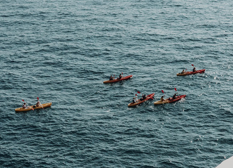 Topdeck travelers rowing out of the port of Dubrovnik in canoes to the crystal blue waters of the Dalmation Coast.