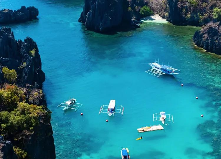 An aerial view of four Boats and two platforms are moored off the crystal blue waters of Palawan Island in the Phillipines.