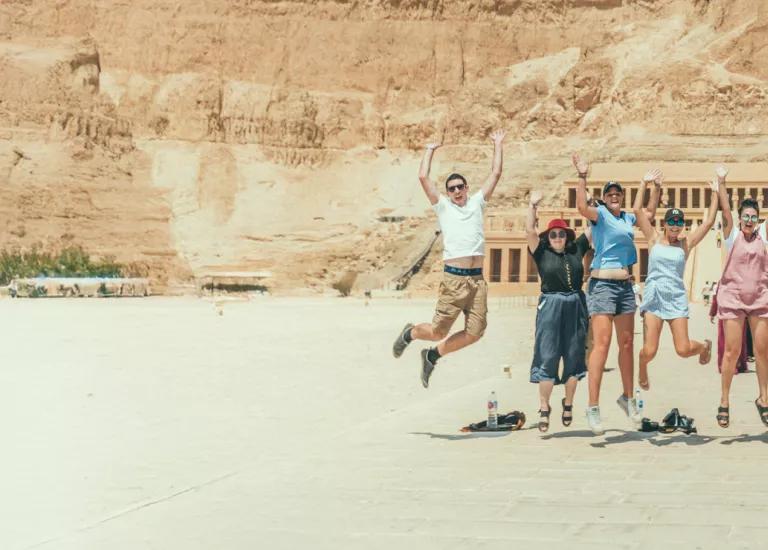 Topdeck travellers posing for a photo together in front of ancient ruins during a trip through the desert.