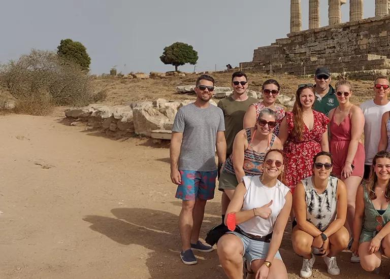 Topdeck travel group posing for a photo beside an ancient pyramid.