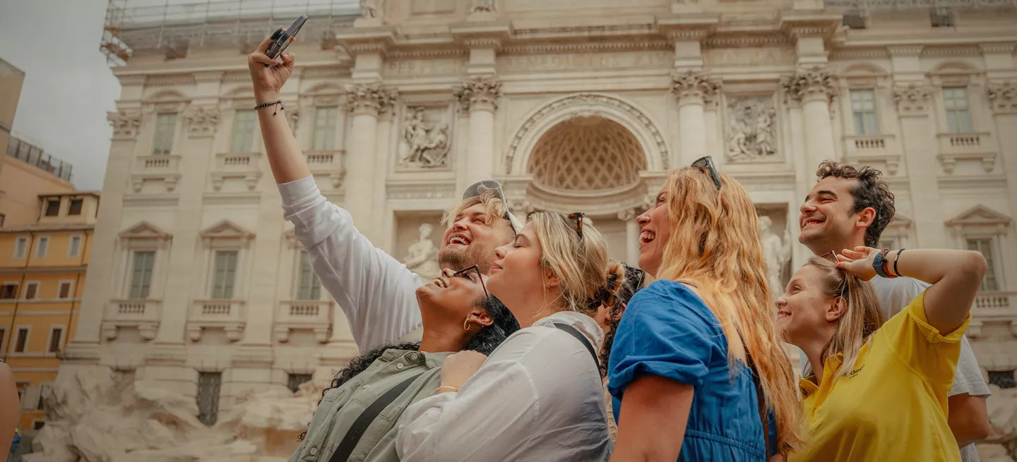 People taking a selfie together in front of the Trevi Fountain in Rome.