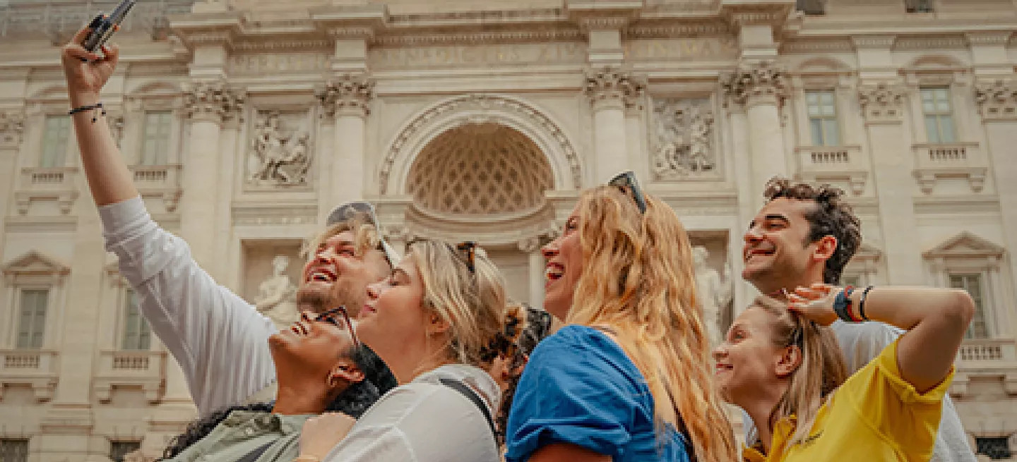 People taking a selfie together in front of the Trevi Fountain in Rome.