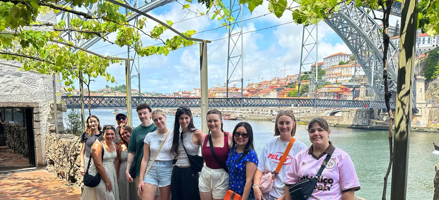 People standing together in front of the Dom Luís I Bridge in Porto, Portugal.