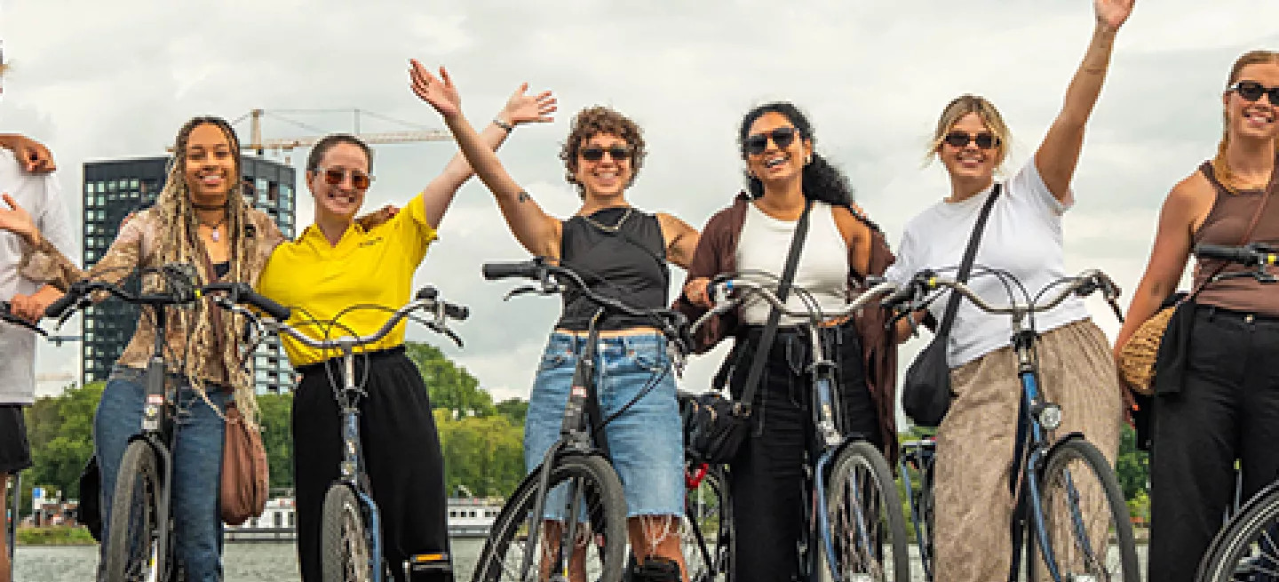 People standing together in a row with bikes near the river in Amsterdam.