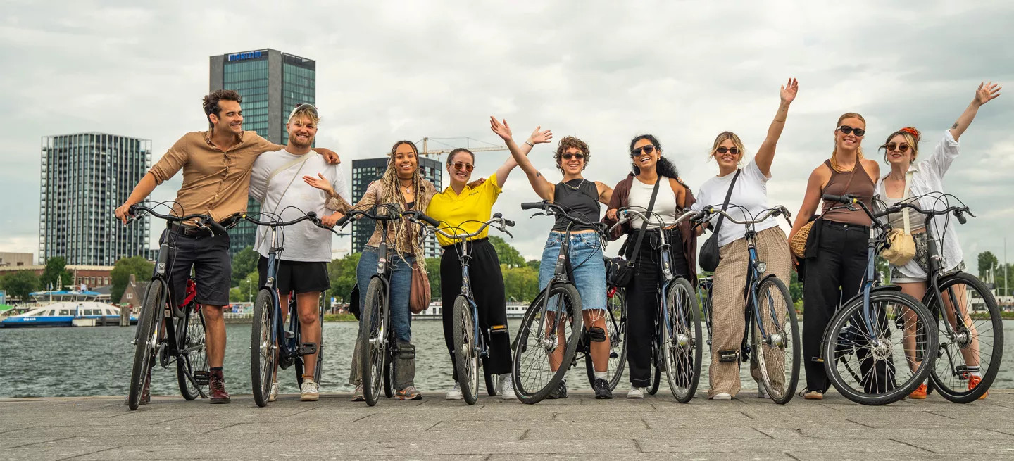 Group of people in a row standing over bikes with their hands in the air in Amsterdam.