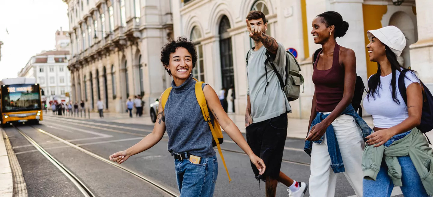 Four people crossing the road in Lisbon. One points in a direction.