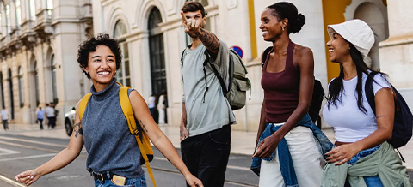Four people crossing the road in Lisbon. One points in a direction.