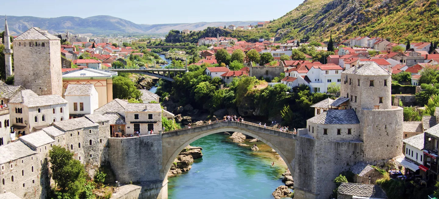People standing on Mostar Bridge over a green river in Mostar, Bosnia and Herzegovina.