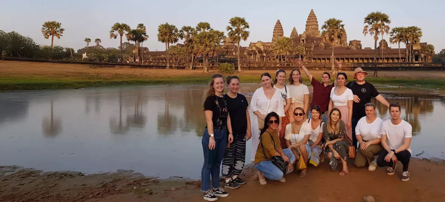 Group of people posing together in front of Angkor Wat in Cambodia.