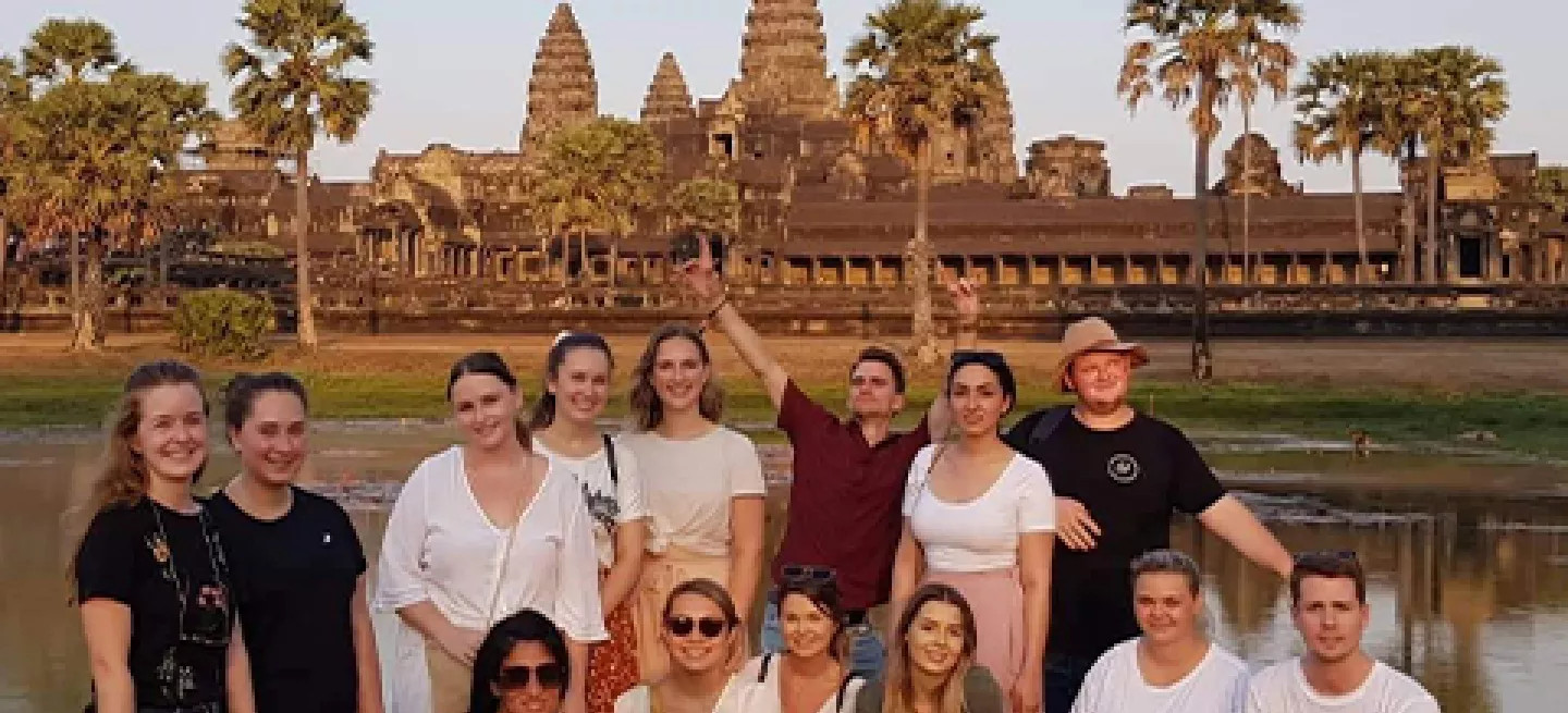 Group of people posing together in front of Angkor Wat in Cambodia.