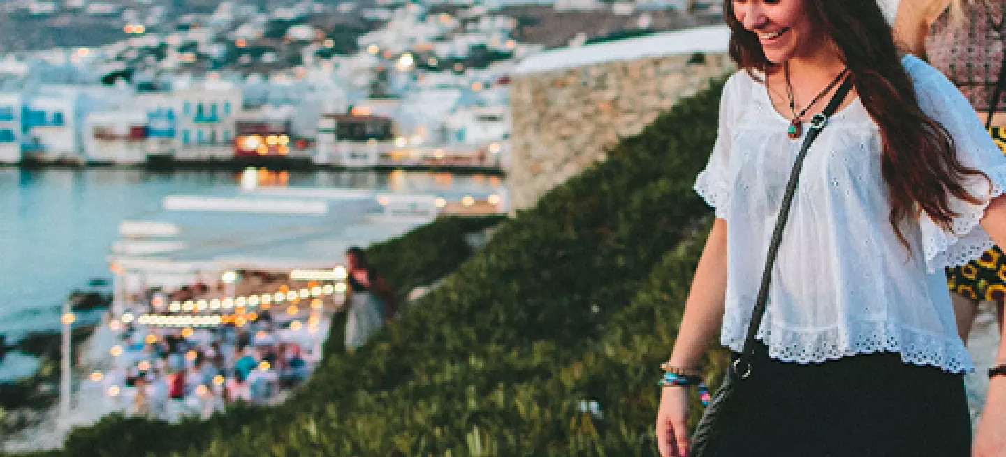 People walking down a slope near the Windmills of Mykonos in the evening.