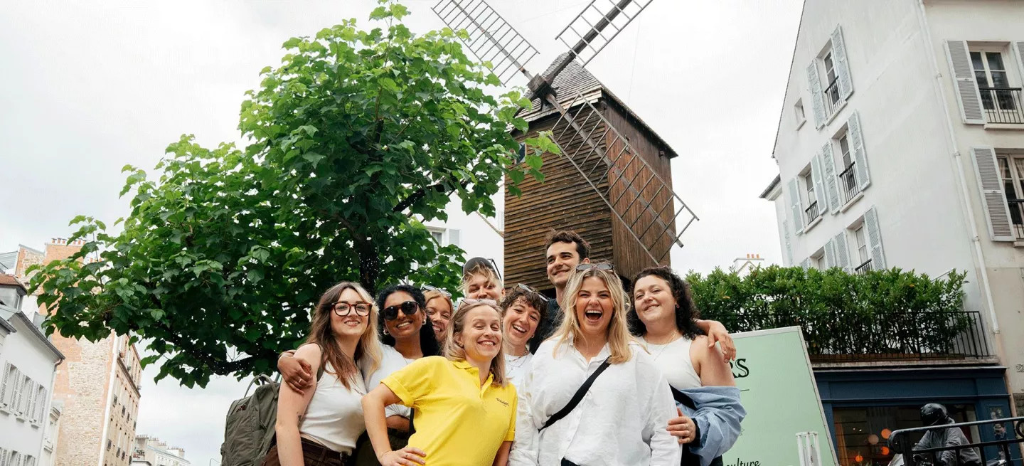 Group of people posing together in front of large windmill.