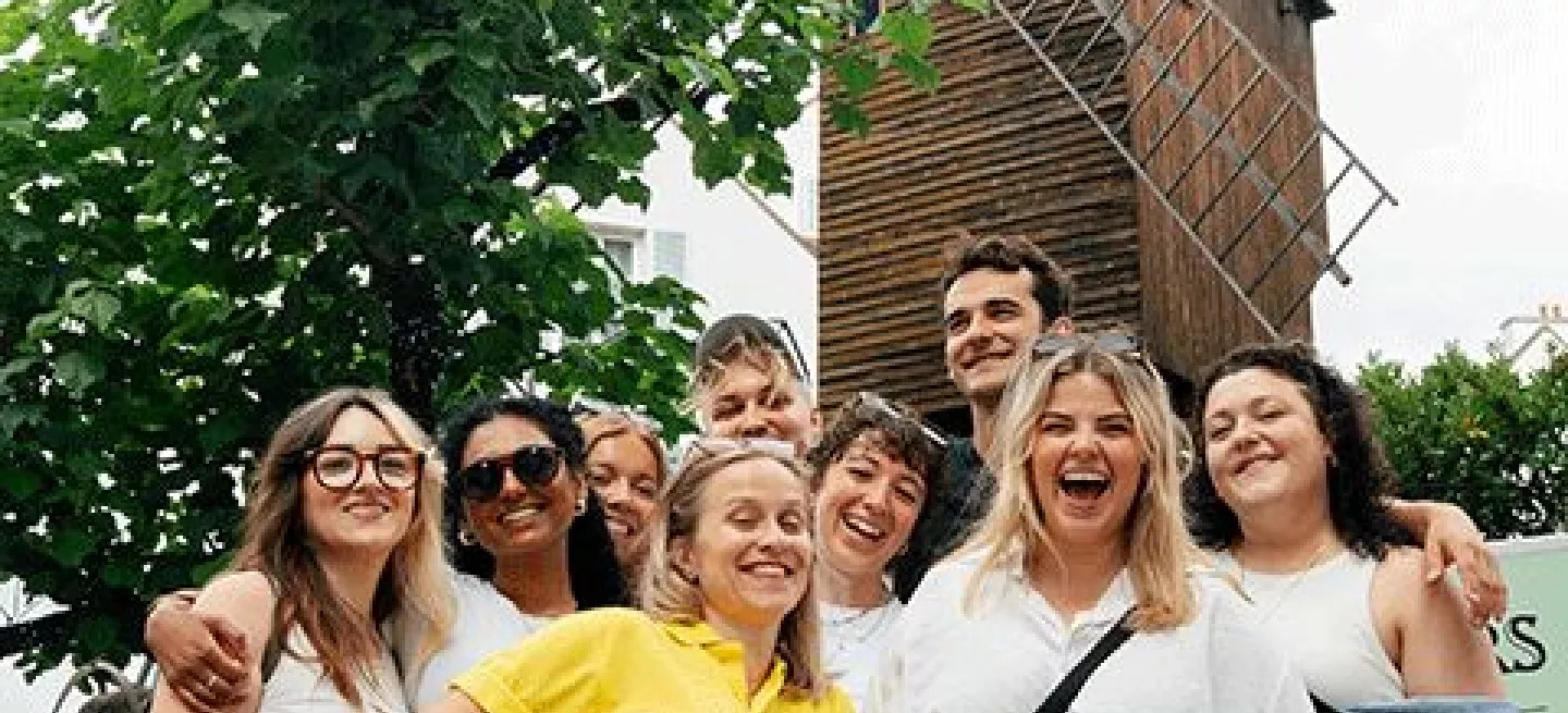 Group of people posing together in front of large windmill.