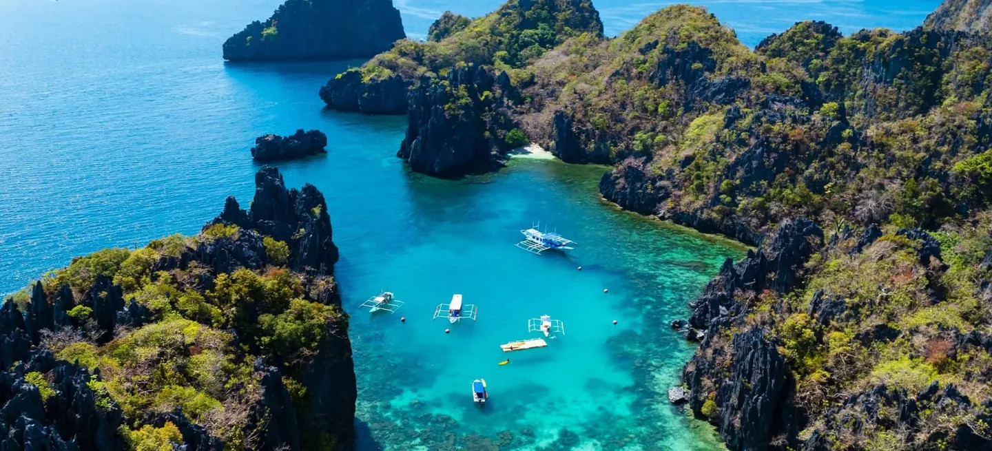 View of a Palawan bay with bright blue water and lush tree covered islands.