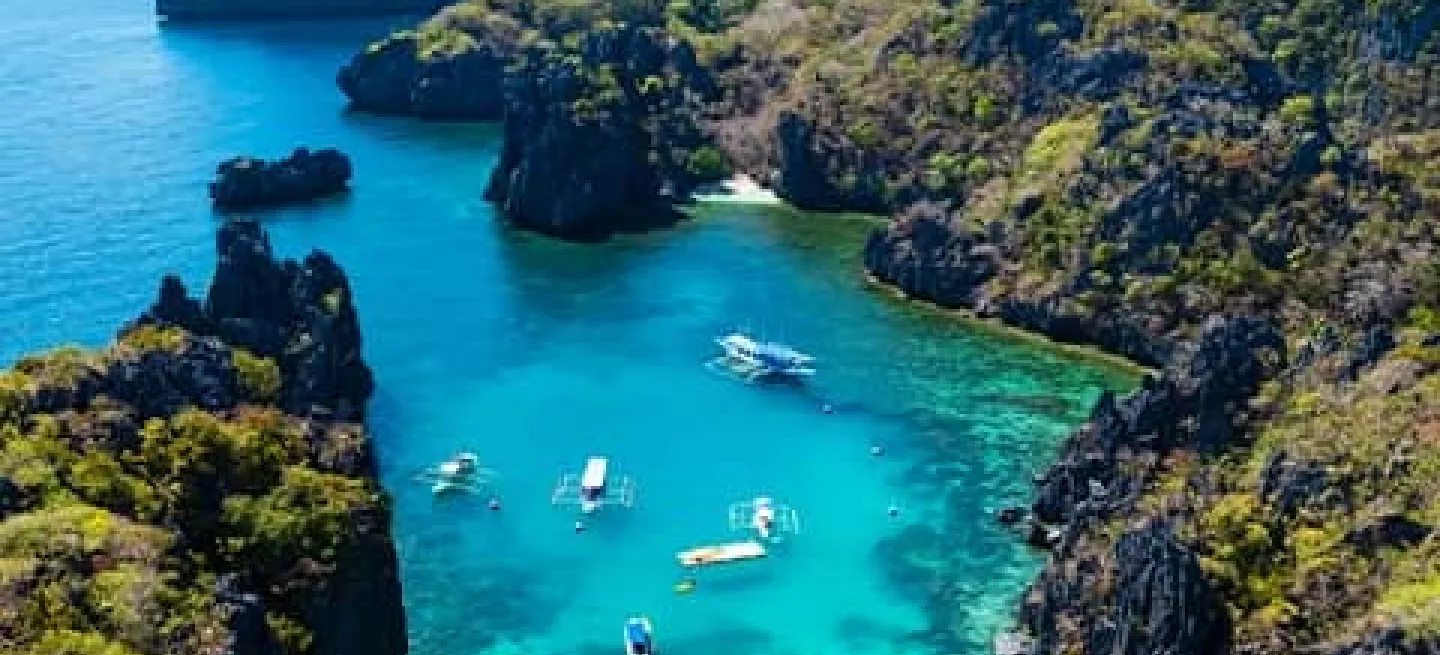 View of a Palawan bay with bright blue water and lush tree covered islands.