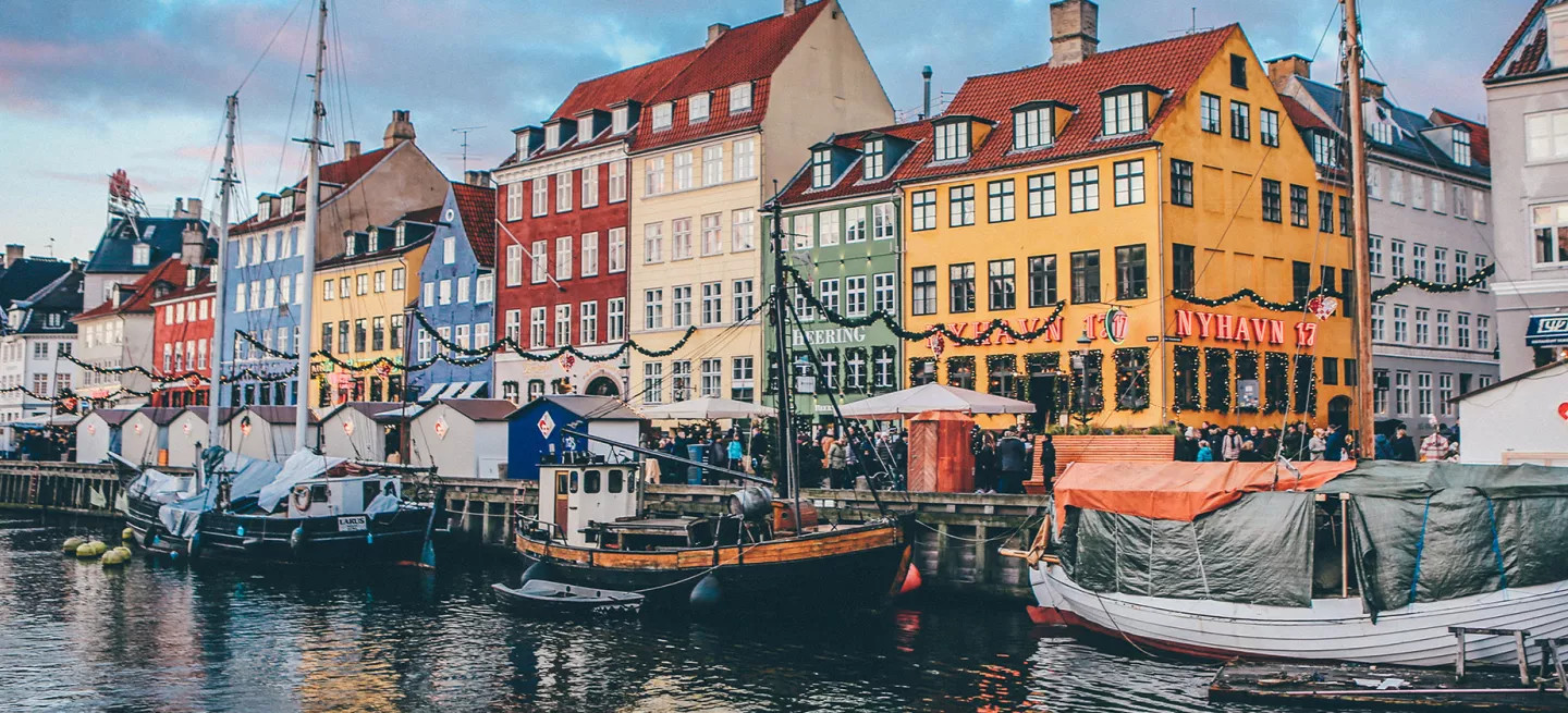 Colourful buildings with Christmas decorations along canal with docked boats.