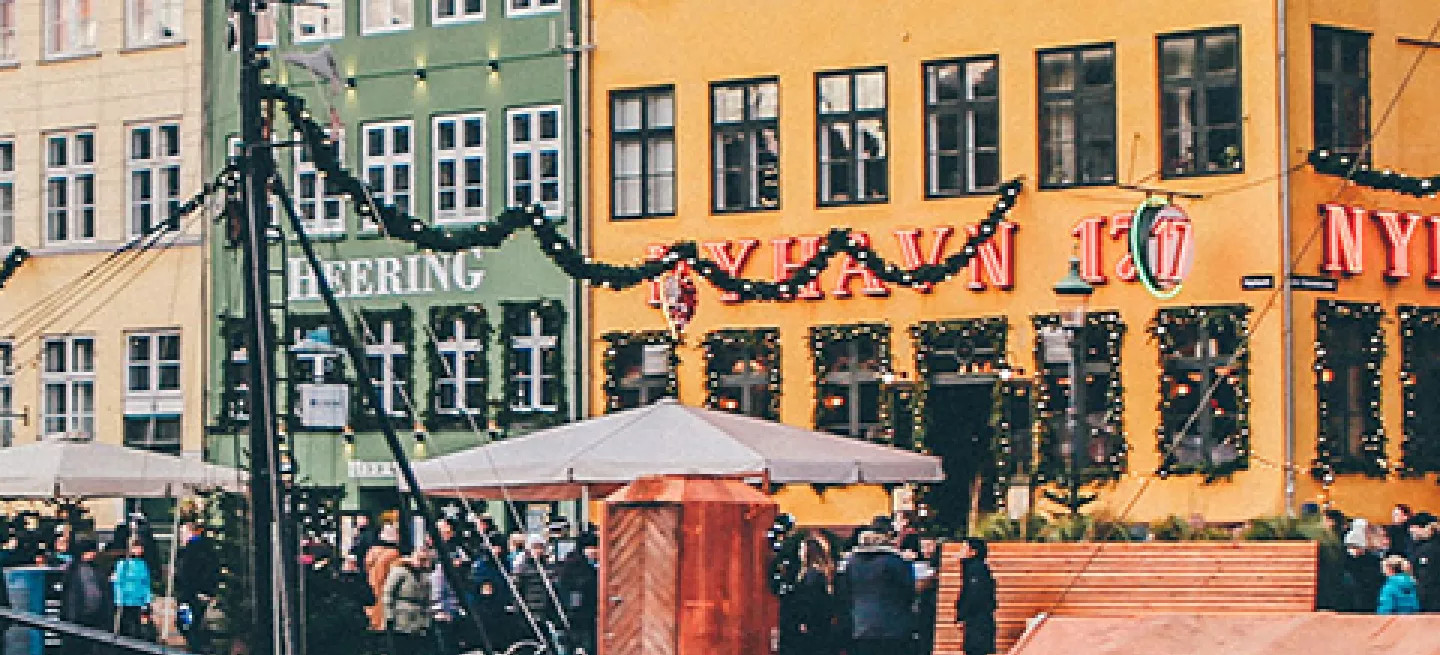 Colourful buildings with Christmas decorations along canal with docked boats.