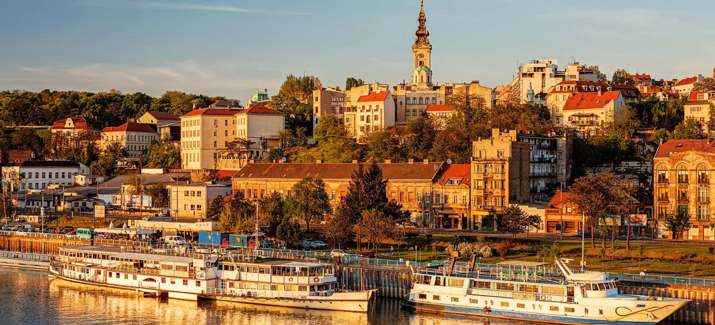 Buildings in the city of Belgrade bathed in warm light at sunset.