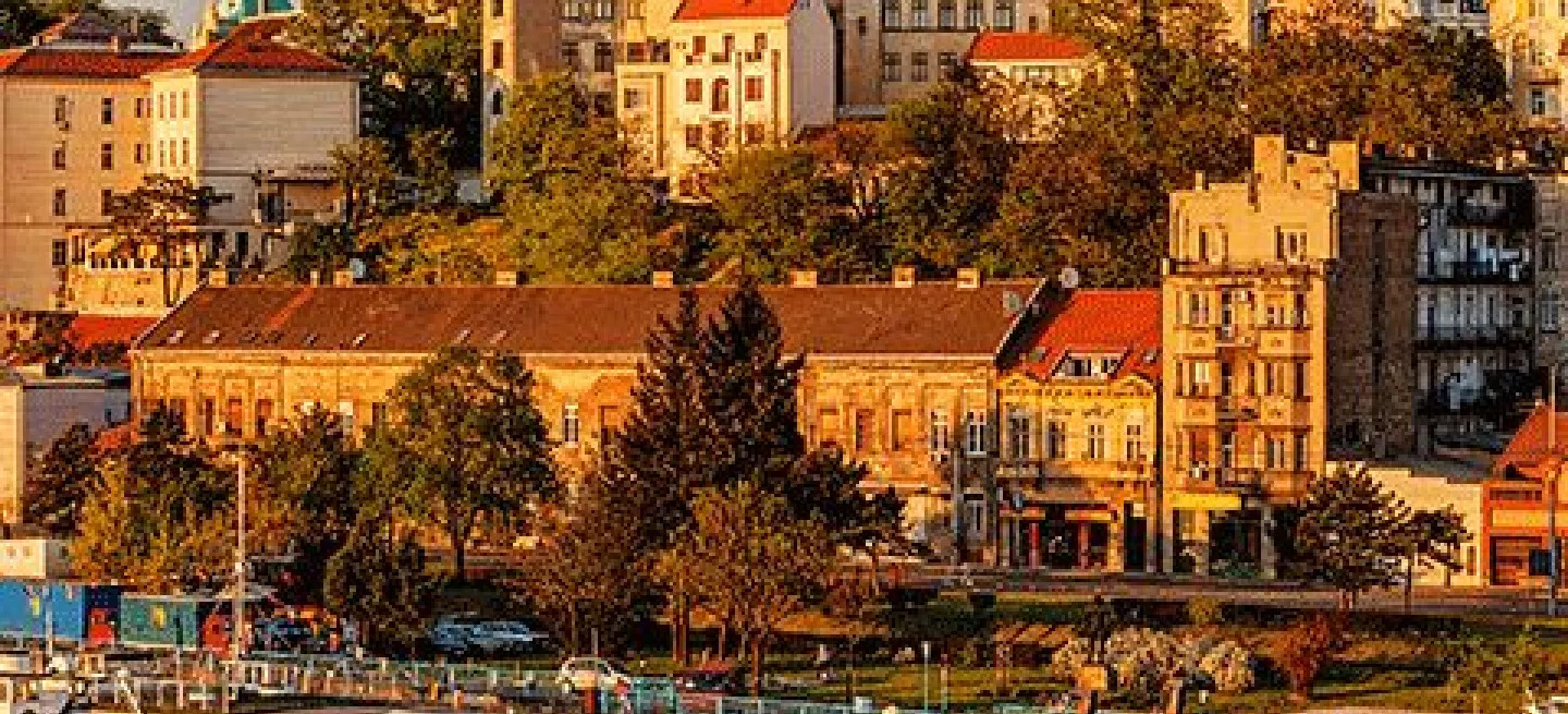 Buildings in the city of Belgrade bathed in warm light at sunset.