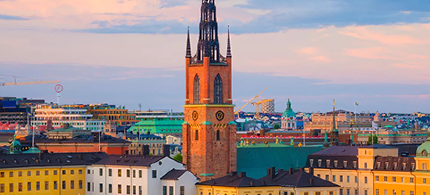 Riddarholm Church with it’s tall spire standing above a body of water where a ship is docked.