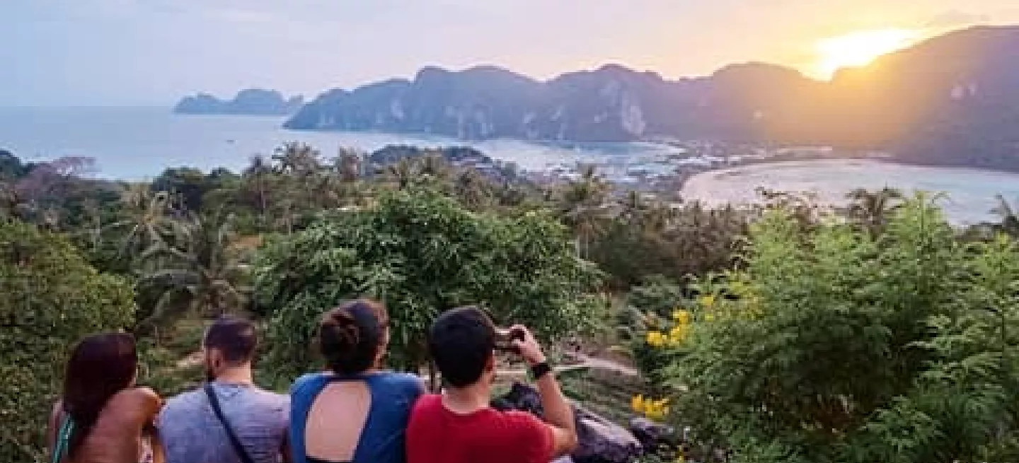 People sitting on rocks at viewpoint, looking out at Koh Phi Phi Don in Thailand.
