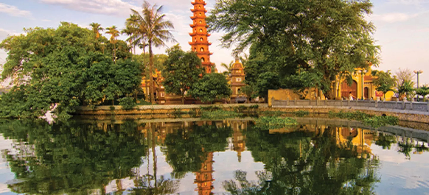 The Tran Quoc Pagoda stands above the trees and reflects out on water nearby in Hanoi, Vietnam.