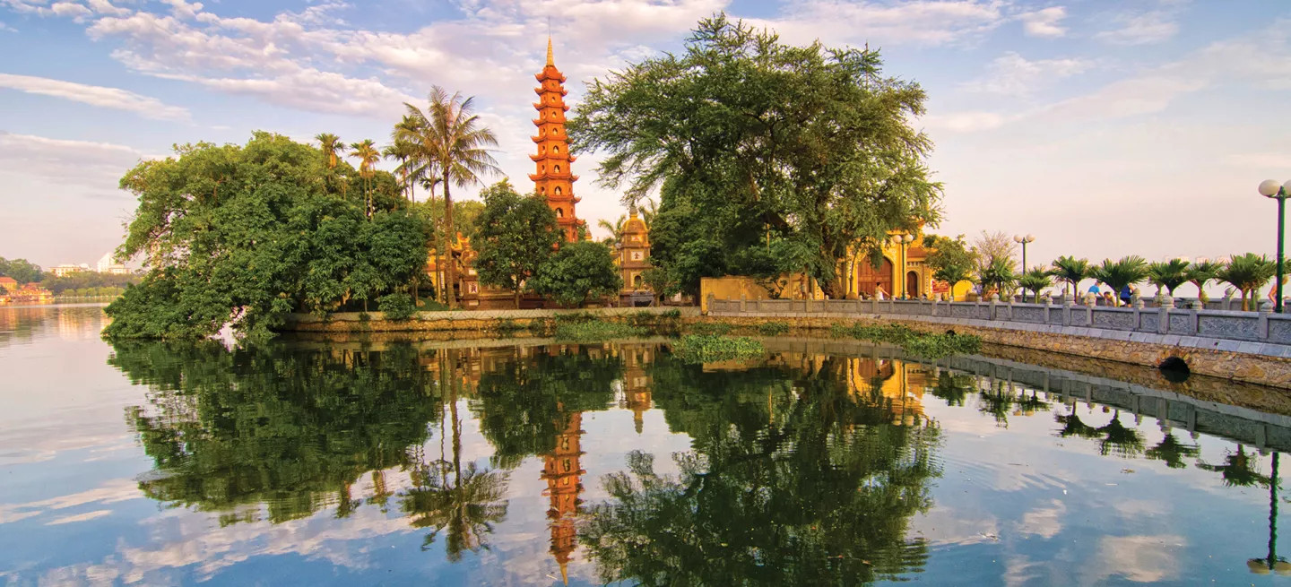 The Tran Quoc Pagoda stands above the trees and reflects out on water nearby in Hanoi, Vietnam.