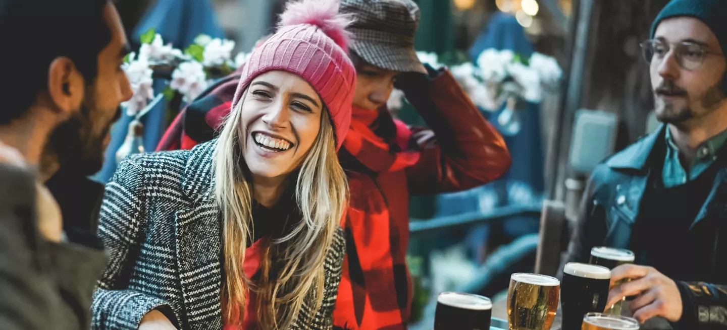Small group of people wearing winter clothing talking at an outdoor restaurant table in Iceland.