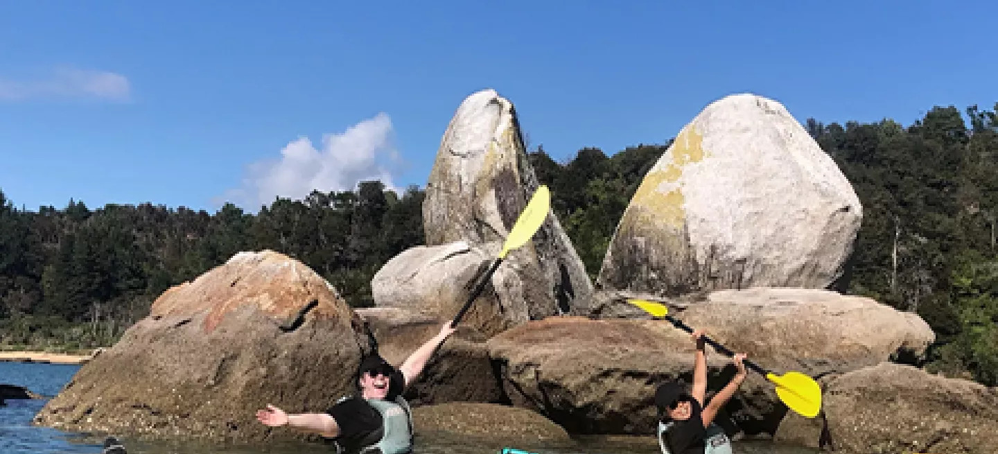Two people are kayaking past Split Apple Rock in the Tasman Bay of New Zealand’s South Island.