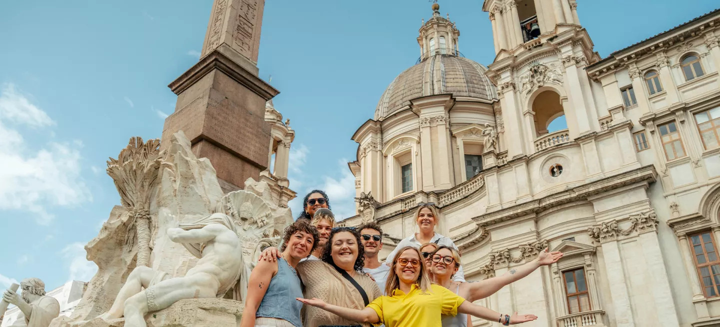 People posing in a group in front of a fountain in Rome.