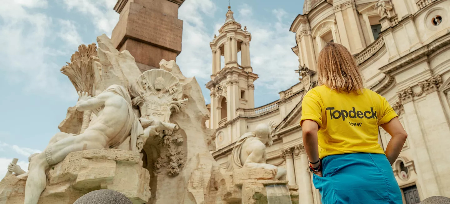 Person wearing a Topdeck uniform looking up at a fountain in Rome.