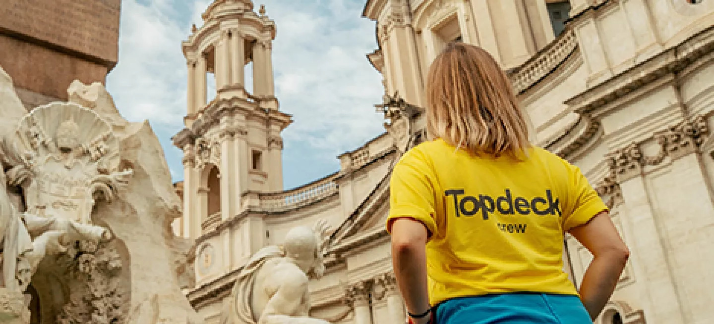 Person wearing a Topdeck uniform looking up at a fountain in Rome.