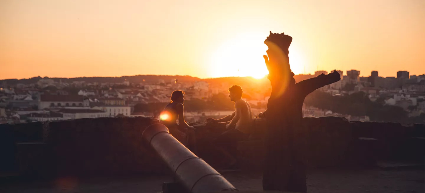 Two people watching the sunset from São Jorge Castle in Lisbon, Portugal.