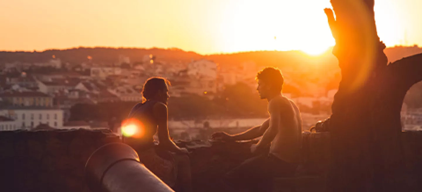 Two people watching the sunset from São Jorge Castle in Lisbon, Portugal.