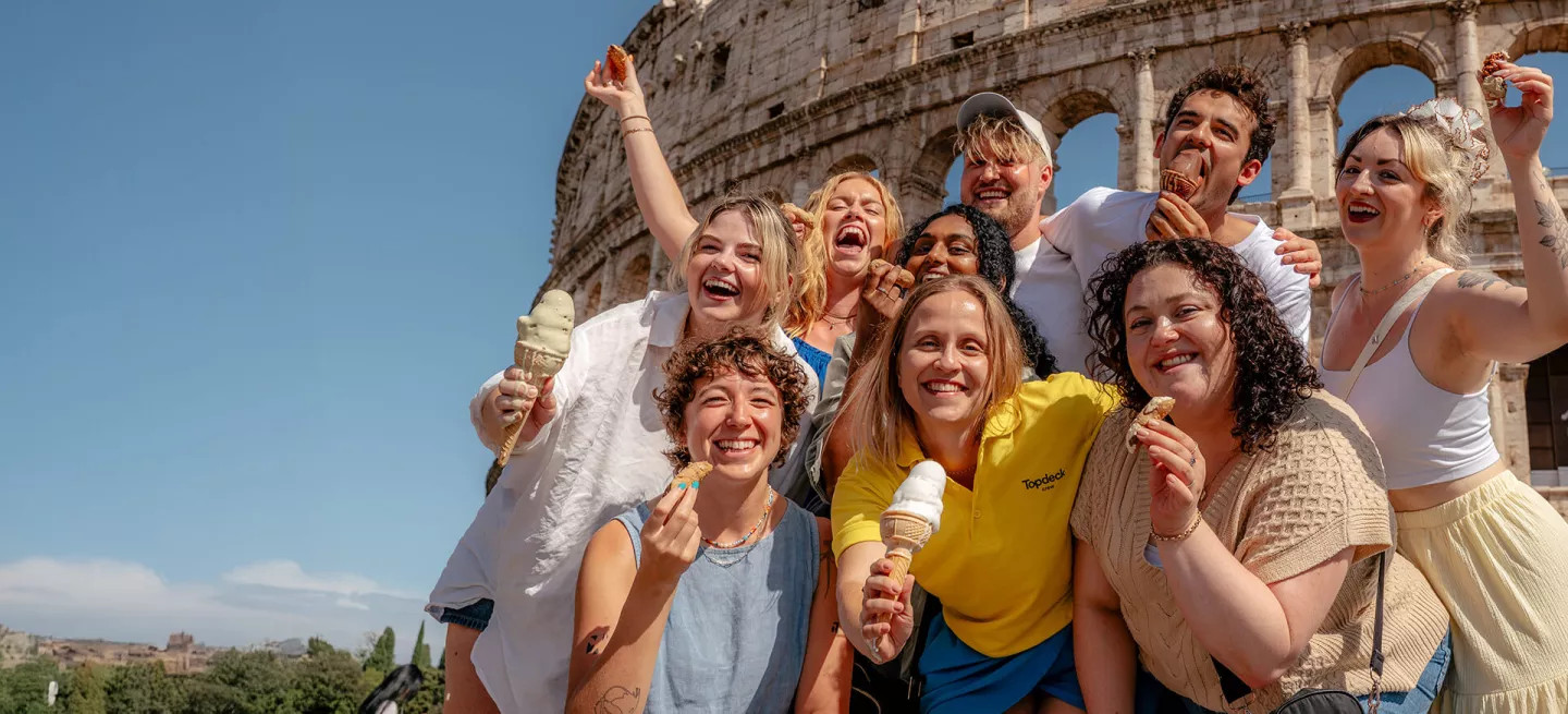 Group of people standing together in front of the colosseum in Rome while holding gelato and cannoli.