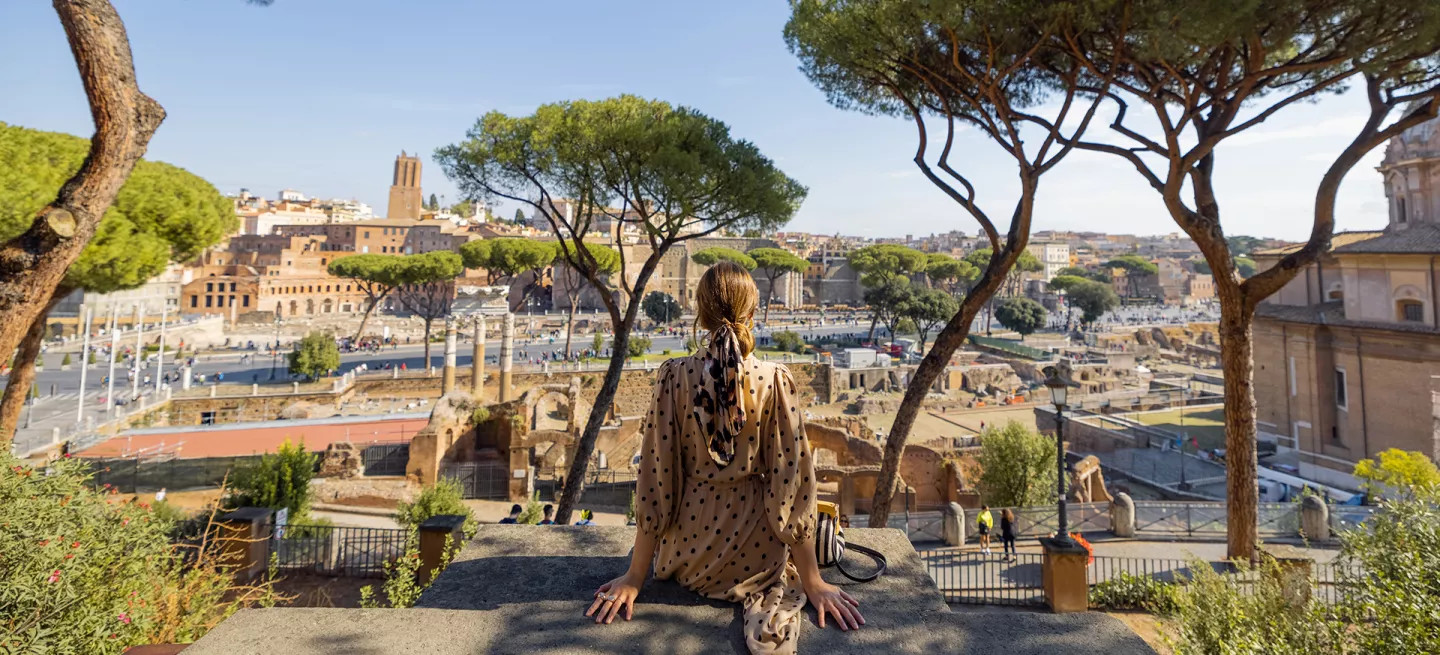 Woman sitting on a wall overlooking Rome in Italy.