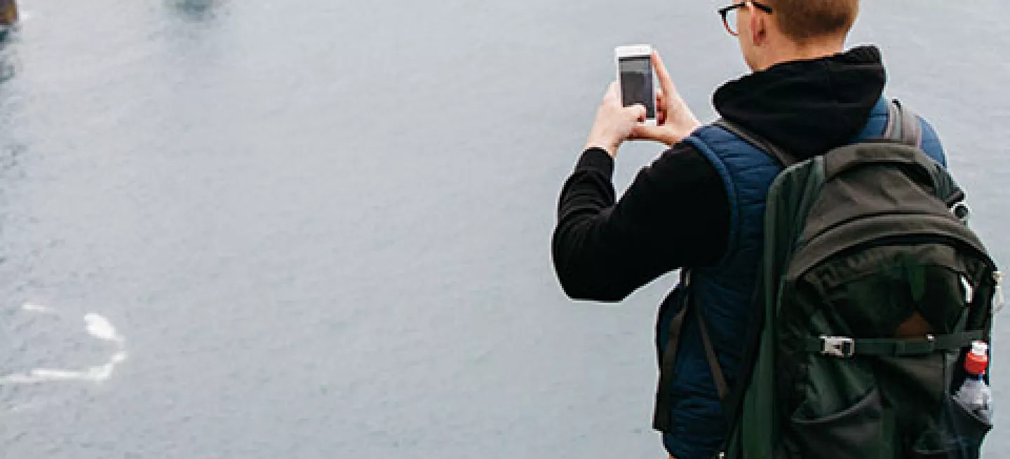 Person taking a photo on their phone of the Cliffs of Moher in Ireland.