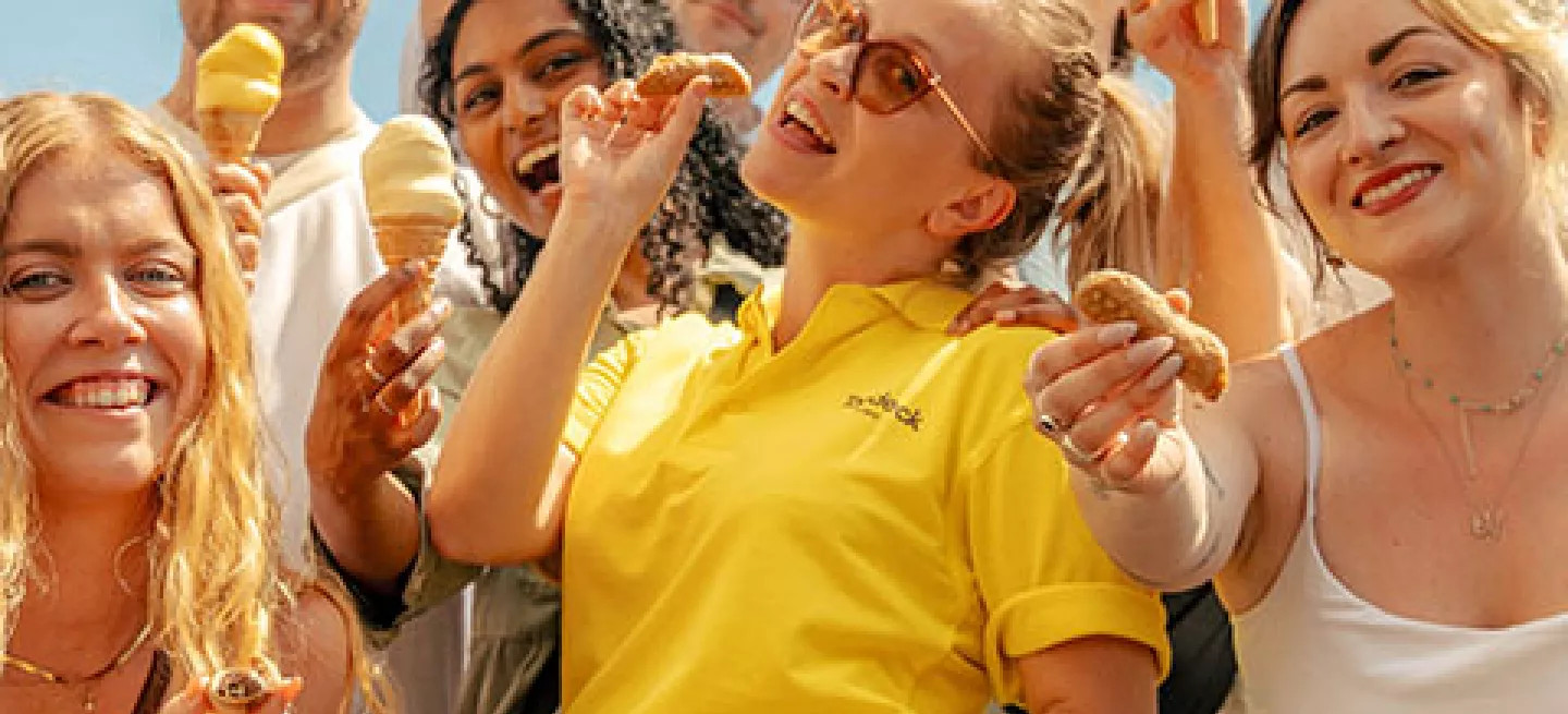 Group of people standing together in front of the colosseum holding gelato.