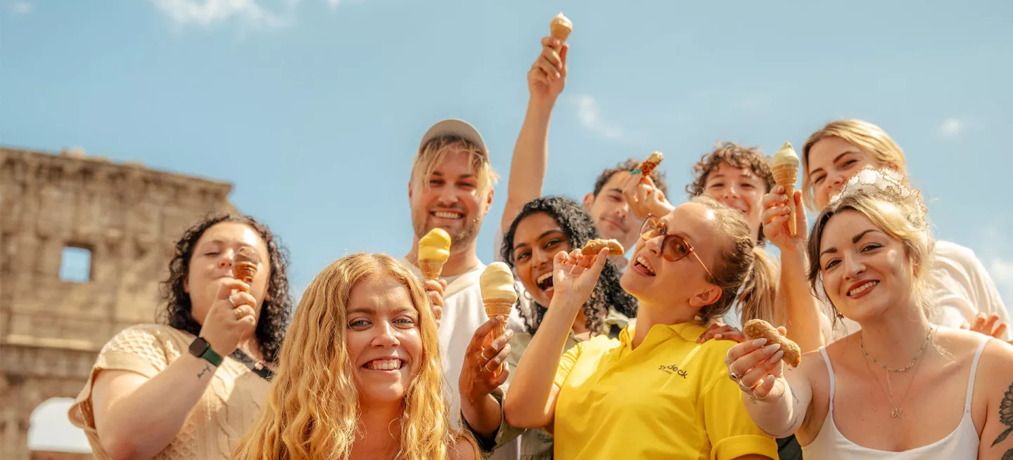 Group of people standing together in front of the colosseum holding gelato.