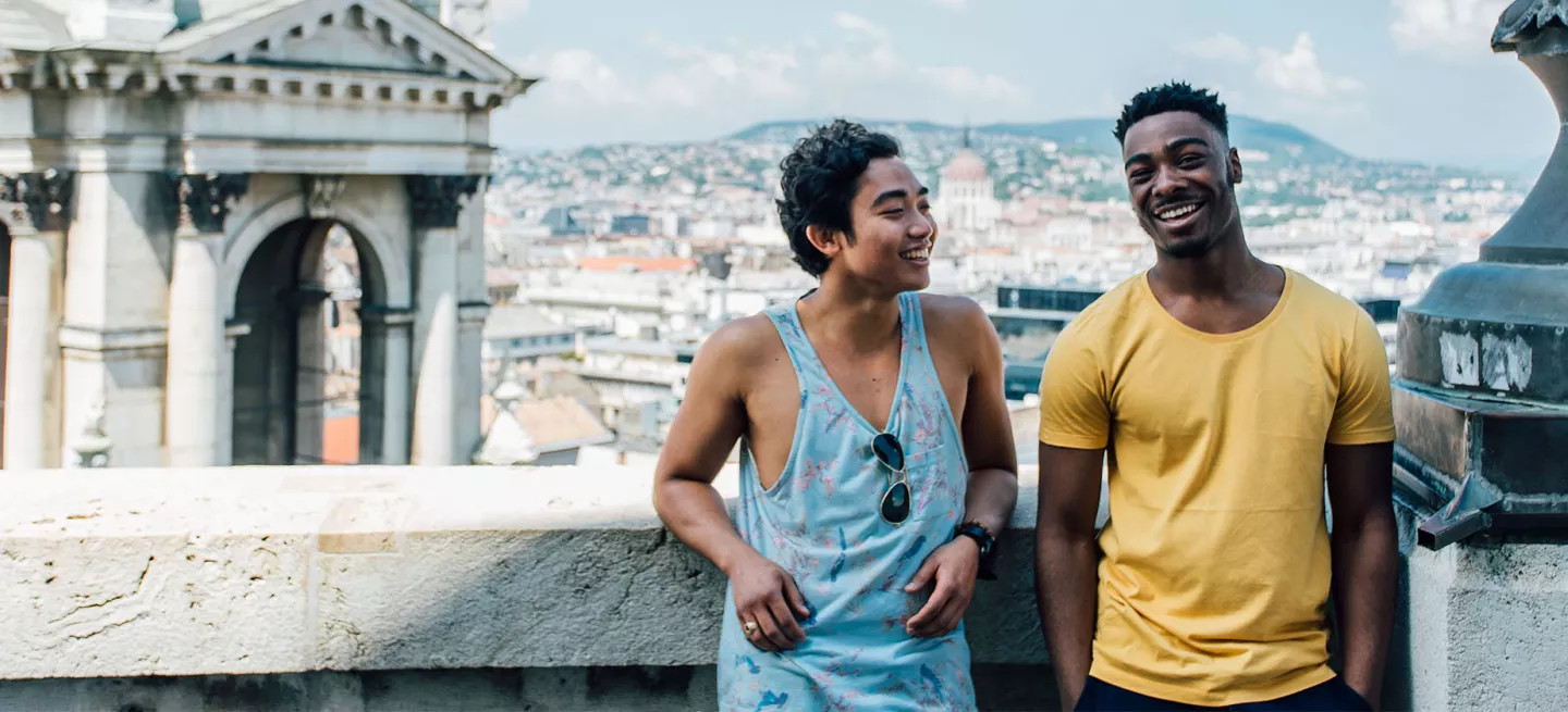 Two people standing together on a balcony in Budapest.