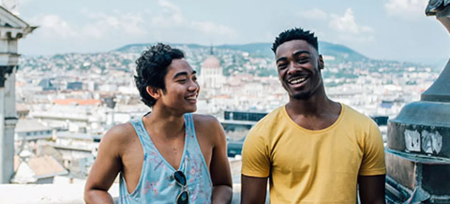 Two people standing together on a balcony in Budapest.