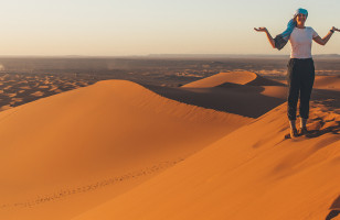 Topdeck Traveler standing alone atop a sand dune in the Sahara Desert during sunset.