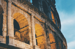 A view of the Colosseum of Rome during dusk, it's exterior lit up.