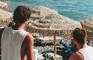 Topdeck travelers hanging around a beach in Mykonos on a sunny day.