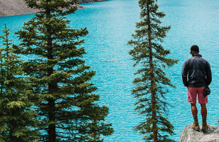 Topdeck traveler, looking out over the clear blue waters of Canada's Morraine Lake.