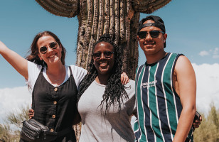 Travellers standing in front of a cactus in the Arizona desert.