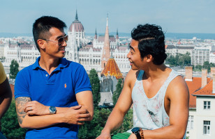 A group of Topdeck travelers chatting with each other in Budapest, with the Hungarian Parliament in the background.